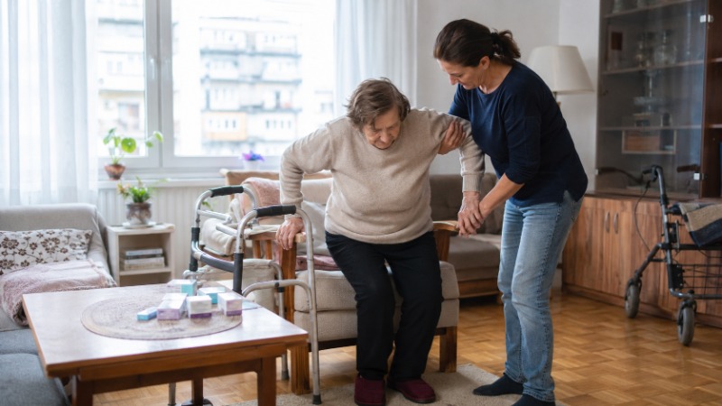 Pečovatelka pomáhá seniorce s běžnými denními úkony v jejím bytě